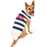 Dog wearing a striped sweater with visible branding on a white background
