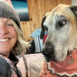 Woman and dog indoors, with the dog wearing a sweater